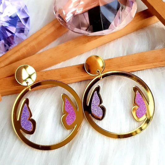 These Butterfly Glitter Hoops Earrings will leave you feeling beautiful and glamorous. Crafted in pretty golden glossy hoops and adorned with glittery purple and pink butterflies, they are sure to be the perfect accessory for any outfit!