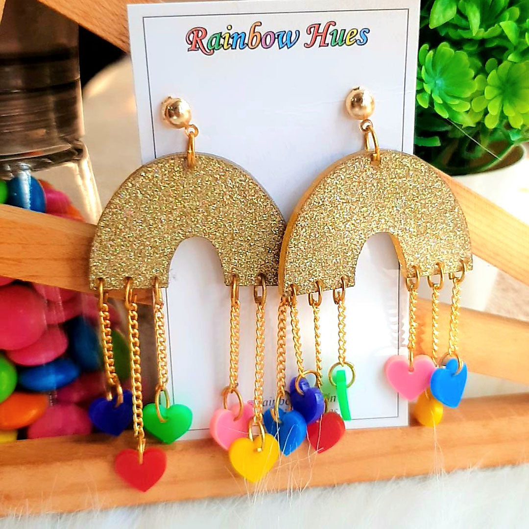 These beautiful Rainbow Little Heart Danglers will add a touch of sophisticated style to your every day look. Crafted with vibrant colours and petite dangling hearts, these earrings will add a sparkle to your day. Plus, the glittery golden rainbow background creates a glamorous finish that's sure to turn heads wherever you go