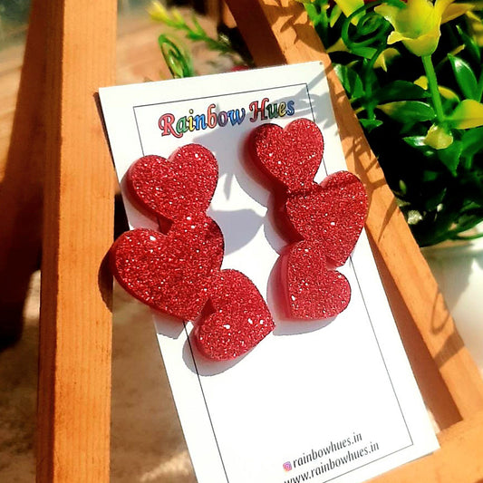 Sparkle with style in these Glitter Tri-Heart Earrings! Shimmering with stunning glitter, these versatile studs will elevate any look. Compliments guaranteed - so beautiful, you'll be glowing!