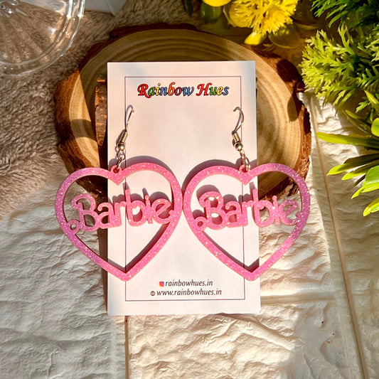 Treat yourself to these fun and flirty Barbie Glitter Heart Earrings! Featuring a heart design with a glittery finish, these earrings will add a pop of glamour and shine to any outfit. Perfect for a night out or a special occasion - show your style and confidence with Barbie!