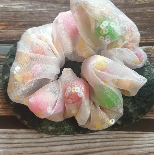 This Rainbow Organza Confetti Pom Pom Scrunchie adds an eye-catching pop of color to any outfit. Crafted from unique organza material, it's filled with pom poms, confetti and sequins for on-trend texture and sparkle. Wear it in your everyday routine for extra flair.