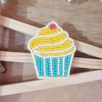 This handmade hairclip has an eye-catching design, featuring a yellow and blue beaded cupcake. Its unique and colorful design will make a statement for any occasion. Crafted with high-quality materials, this cupcake hairclip is sure to last for years.