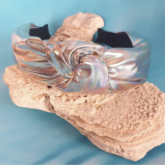 Be the envy of everyone around you with this stunning Holographic Top Knot Hairband. The soft shiny material dazzles with a spectrum of rainbow colors at any angle to give you a unique and eye-catching look. Make a statement with this timeless style.