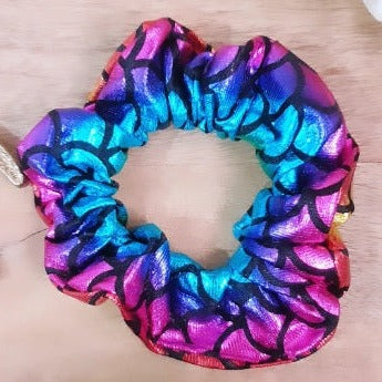 This Rainbow Metallic Dual Tone Scrunchie is a unique and stylish addition to your hair accessories. Featuring a shiny finish, this dual tone scrunchie is sure to add a splash of color to your outfit. Perfect for adding an elegant touch to any look.