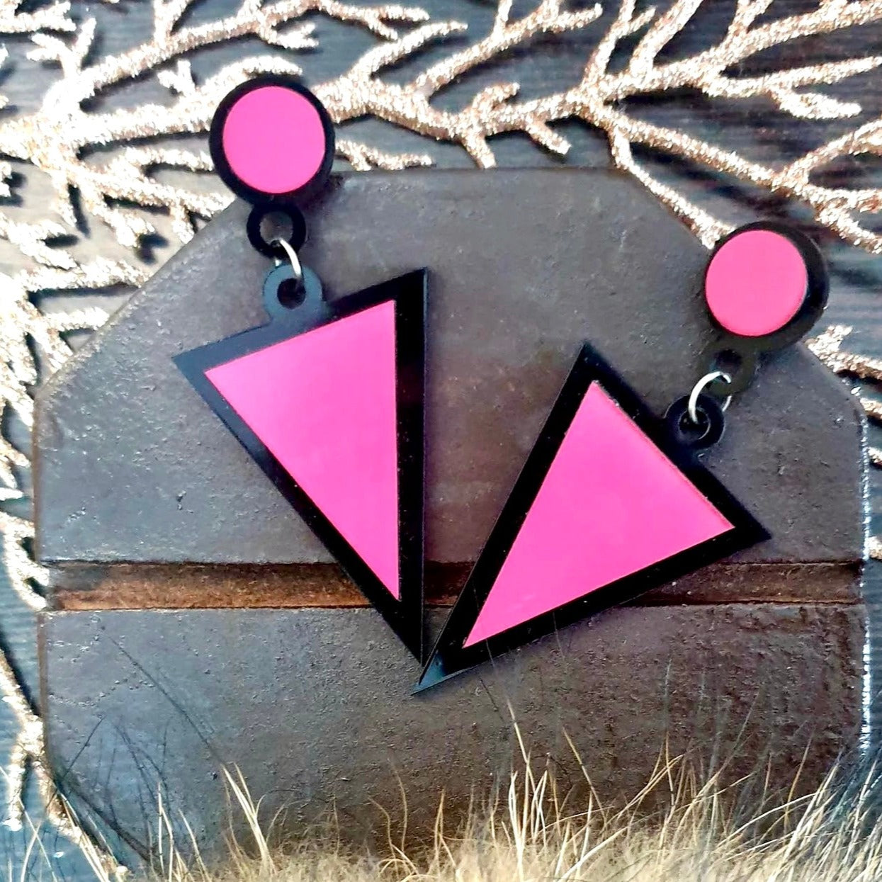 These statement-making Pink Triangle Earrings are perfect for adding a contemporary accent to any look. The bold black and hot pink design is edgy and eye-catching, making them an ideal accessory for any stylish wardrobe.