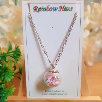 This Rainbow Star Shaker Globe Necklace will add a pop of shine and colour to your wardrobe! Wear something special that will make everyone smile with this eye-catching piece full of shiny multicolour star sequins and delicate glass globe. For a unique and stylish look, wear this Rainbow Star Shaker Globe Necklace!