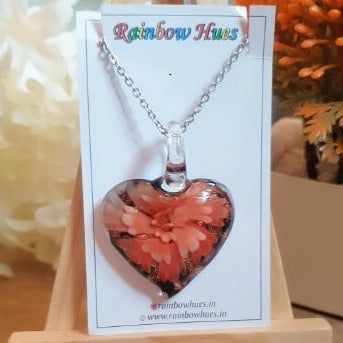 This gorgeous glass heart necklace with a stunning orange floral detail is the perfect statement piece. Handmade with love, each necklace is unique, offering a truly special look that will turn heads. Sparkling and vibrant, it's ideal for showing off your style!
