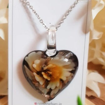 This Cream Floral Heart Glass Necklace is the perfect gift for any special occasion. Each piece is handcrafted with a beautiful glass heart pendant, adorned with a beige flower detailing for a timeless elegant look. Every necklace is one-of-a-kind, ensuring a unique and unforgettable gift. Show someone special how much you care with this heart necklace!