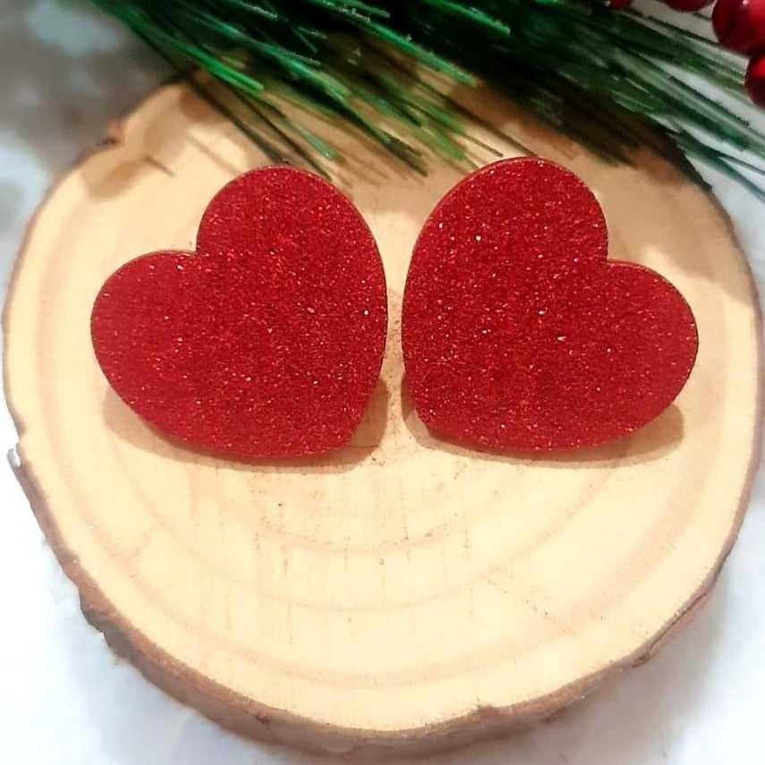 Fall in love with these sparkling Red Glitter Heart Studs! Add a touch of glamour to your look with these glimmering, eye-catching earrings. Perfect for a night out or an evening date, these earrings will light up your style!