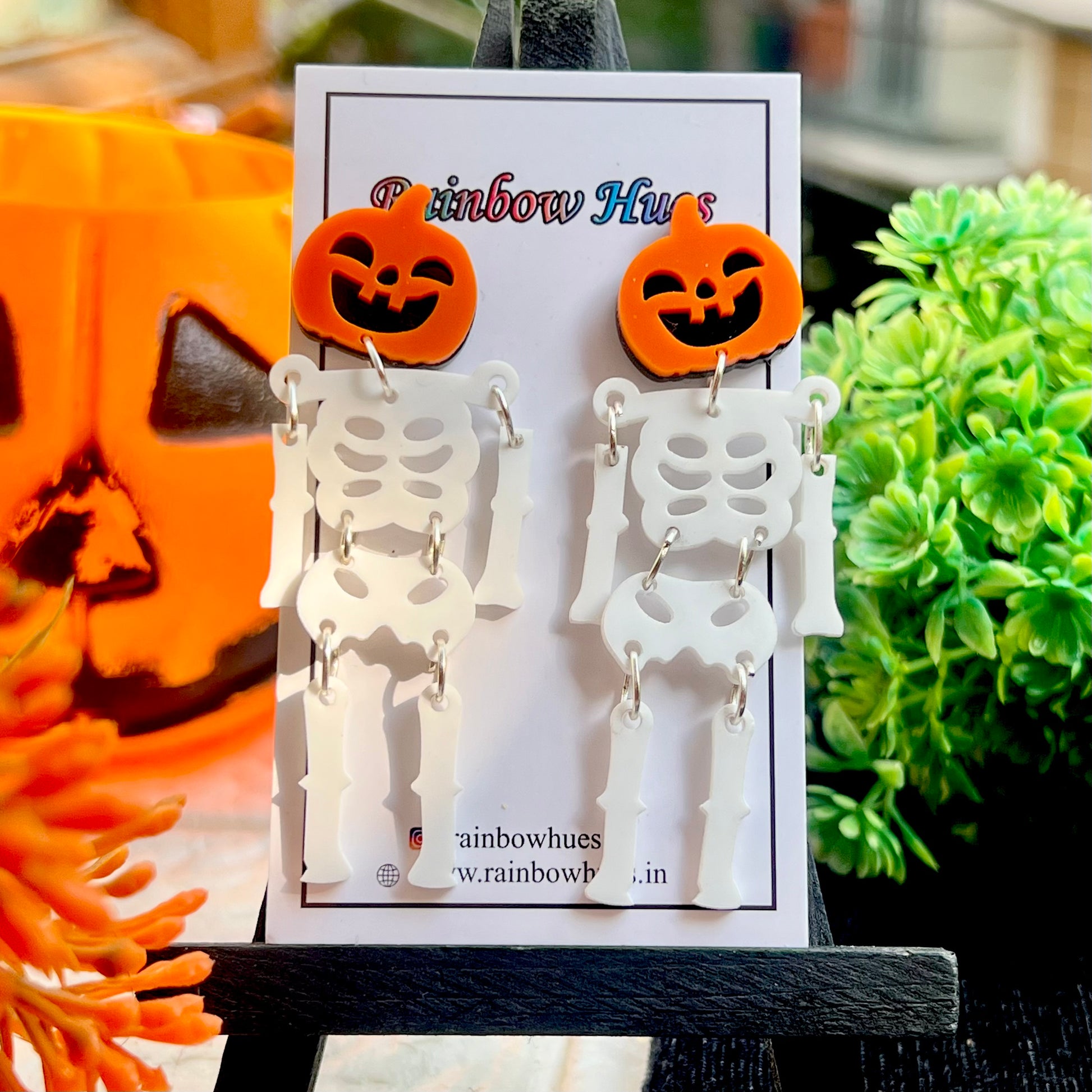 Halloween-themed earrings with skeleton design on a display card, with pumpkins